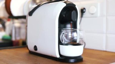 Kahve cam bardağa akar. Kahve makinesini yavaş çekim yapan adamın elini hazırlanmış sıcak içecek sabahına yaklaştırır. Kahvaltıda içecek.