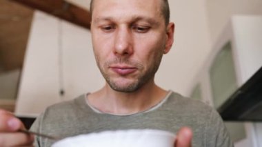 Aç beyaz adam evde, mutfakta kahvaltıda sağlıklı mısır gevreği ve süt yiyor. Beslenme ve yemek konsepti.