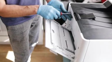 Yazıcı tamircisi. Erkek bir tamirci, müşterisinin dairesinde onarımlara başlamadan önce lazer yazıcıyı kontrol eder..