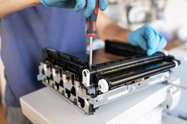 Yazıcı tamircisi. Erkek bir tamirci, müşterisinin dairesinde onarımlara başlamadan önce lazer yazıcıyı kontrol eder..