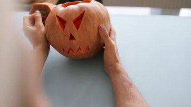 Cadılar bayramı balkabağını oymanın son dokunuşları, adam balkabağının ağzından bir parça çıkardı. Geleneksel bir Cadılar Bayramı Sembolü.