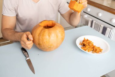 Cadılar Bayramı 'nda balkabağından fener yapma süreci. Adam evde Cadılar Bayramı Balkabağı oyuyor.