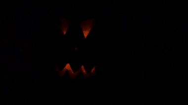 Siyah arka planda parlayan gözleri olan korkunç Cadılar Bayramı balkabakları.