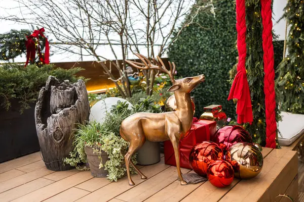 Evin verandasının Noel süslemesi. Verandada fener ve kırmızı noel süslemeleri var..