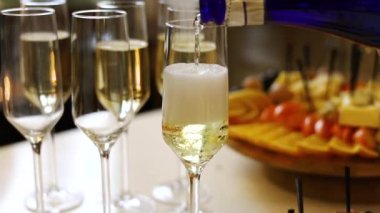 Kadın şampanyayı mutfakta şarap bardaklarına dolduruyor. 