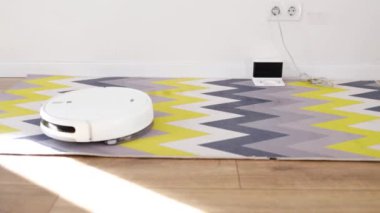 Otomatik robot elektrikli süpürge hareket ediyor ve halıyı temizliyor. Akıllı ev teknolojileri