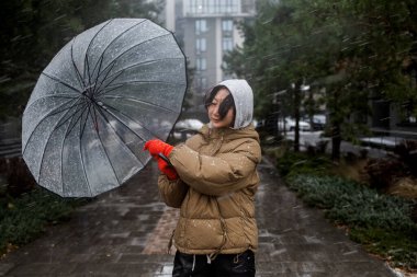 Kışın şiddetli rüzgar ve kar altında şemsiyesini tutmaya çalışan Asyalı kadın..