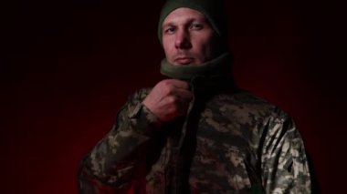 Taktik yüz maskesi takan ve karanlık arka planda duran genç, ciddi bir erkek Ukrayna askerinin portresi..