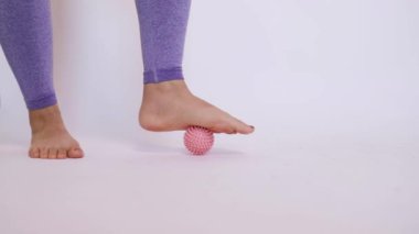 Çivili bir masaj topunun üzerinde bir kadının ayağının yakın çekimi.. 
