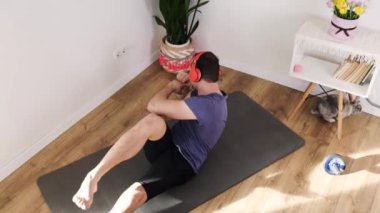 Orta yaşlı bir adam oturma odasında tavşanla yoga minderinde egzersiz yapıyor..