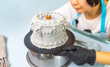 Female confectioner decorating cake in kitchen, Confectioner is decorating creamy cake, cooking class, culinary, bakery, food and people concept. clipart