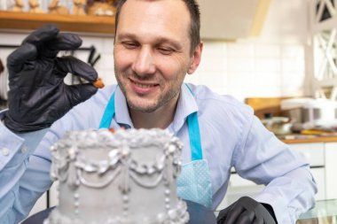 Mutfakta pasta şefi fındık pastasını dekore ediyor, şekerlemeci çikolatalı pasta, yemek kursu, aşçılık, fırın, yemek ve insanlar konseptini süslüyor..