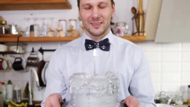 Kafkasyalı mutlu orta yaşlı adam portresi parti şapkalı yalnız yetişkin adam elinde mumlar söndürüyor gözlerini kapatıyor evde tek başına doğum gününü kutluyor.
