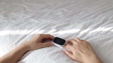 Kadın, Nabız ve Oksijen Doygunluğunu Evde Nabız Oksimetresi kullanarak Ölçüyor. Yakın plan. Cihazın üzerinde sensörler ve göstergeler olan bir arama. Kalp atışlarının, nabzının, kalp atışlarının ölçümü.