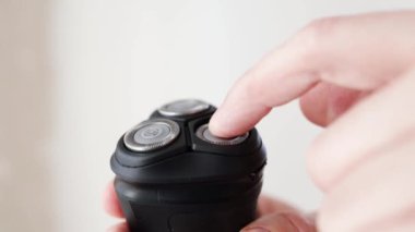 Sakalını elektrikli traşla tıraş eden bir adam. Elektrik Usturası 'nı kontrol et. Bıyık tıraşı tamiri. Parçalanmış kırpıcı yakın plan.