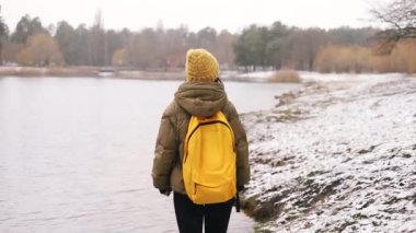Karlı bir kış günü ormanda, sırt çantalı, karlı, taze, beyaz bir karla yürüyen bir kadın. Kış tatilindeki kadın turist. 