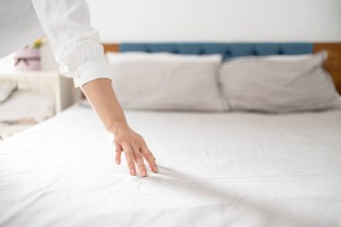 Otel hizmetçisi otel odasını temizler ve yatağı toplar..