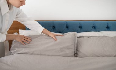 Otel hizmetçisi otel odasını temizler ve yatağı toplar..