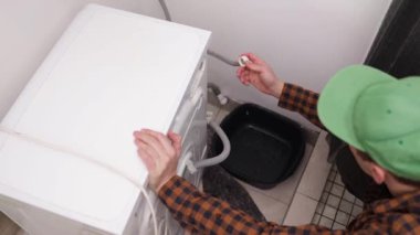 Tamirci arka tarafta çamaşır makinası var. Çamaşır makinesi servis konsepti. Su kaynağı aygıta bağlanıyor.