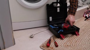 Çamaşır makinesini tornavidayla söken bir ev aletleri tamircisi. Ev aletlerinin profesyonel onarımı.