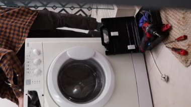 Çamaşır makinesini tornavidayla söken bir ev aletleri tamircisi. Ev aletlerinin profesyonel onarımı.