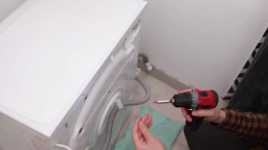 Çamaşır makinesini tornavidayla söken bir ev aletleri tamircisi. Ev aletlerinin profesyonel onarımı.