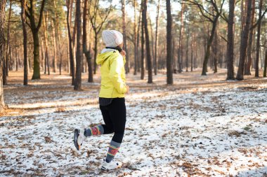 Asyalı orta yaşlı bir kadın son derece soğuk ve karlı bir günde dışarıda koşup egzersiz yapıyor. Spor ve spor motivasyon teması. 