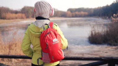 Sırt çantalı turist, kışın göl manzarasının keyfini çıkarıyor. Kadın, sırt çantası ve göl kenarında yürüyüş, dinlenme, perspektif ve doğa tatilinde hafıza.. 