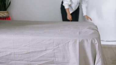 Yatağı yapan kadın, yatak odasındaki yumuşak yastıkları kabartıyor. Genç Asyalı kadın yatak odasını temizler ve yatağını toplar..