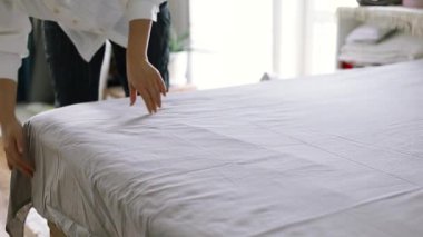 Yatağı yapan kadın, yatak odasındaki yumuşak yastıkları kabartıyor. Genç Asyalı kadın yatak odasını temizler ve yatağını toplar..