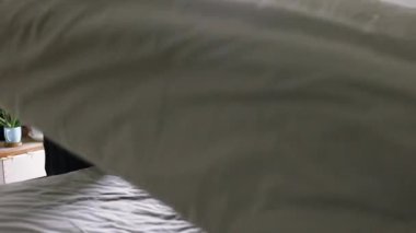 Yatağı yapan kadın, yatak odasındaki yumuşak yastıkları kabartıyor. Genç Asyalı kadın yatak odasını temizler ve yatağını toplar..