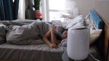 Yatak odasında hava nemlendiricisiyle uyumak, daha iyi bir uyku için nemi arttırmak..