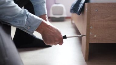 Rehber kullanarak otomatik montaj. Ev tasarımı. Yatağın kenarına vida yerleştirmek için altıgen kullanan bir adamın ellerinin ahşap bir yatak montajı. Tahta mobilya koleksiyonu. Bir saatliğine kocacığım..