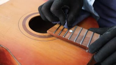 Gitar tamircisi akustik gitarı temizliyor. Panoyu silmek için temiz bez, yakın plan.
