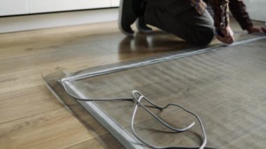 Pencere örgü ören ellere yakın çekim. Parmaklar ağ ile çerçeve kanalına basar. Bulanık arka plan, kapalı mekan ayarlarını gösteriyor. Ekran malzemelerinin korunması üzerine titiz ve detaylı çalışmalara odaklanın