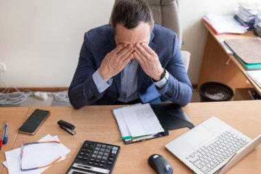 Küçük işletme sahipleri mali kriz, yüksek maliyetler, banka borcu, aşırı harcama kavramı yaşıyor. Masada oturan adam dizüstü bilgisayar ekranına bakıyor. Masrafları hesapladıktan sonra makbuz kendini çaresiz hissediyor.