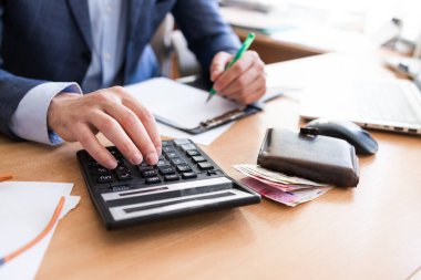 Adam aile içi faturaları evde hesaplayın. Modern ofiste hesap makinesini kullanarak iş adamı. Genç erkek denge ve maliyetleri kontrol etmek. Finans saymaya başla. Vergi ödeme için evrak işi iş adamları