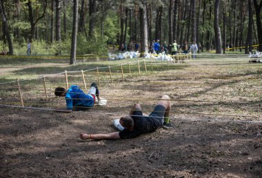 Açık hava engelli parkurunda ağ altında sürünen, animasyona katılan biri. meydan okuma, macera, yarış, fitness, takım çalışması, açık hava