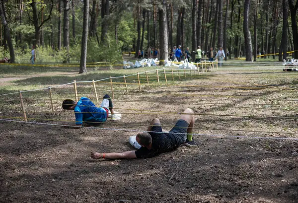 Açık hava engelli parkurunda ağ altında sürünen, animasyona katılan biri. meydan okuma, macera, yarış, fitness, takım çalışması, açık hava