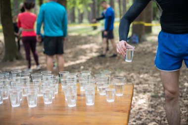 Yorgun spor müsabakalarına katılanlar bir bardak su içiyorlar. Koşucular su içer, sporcular suya koşar..