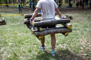 Genç sporcu engelli yarış pistinde kütük taşıyor..