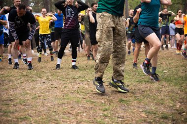 Kiev, Ukrayna - Mayıs 2025: Bir orman macerası parkında engelli yarış sırasında grup açık hava fitness aktivitesi.