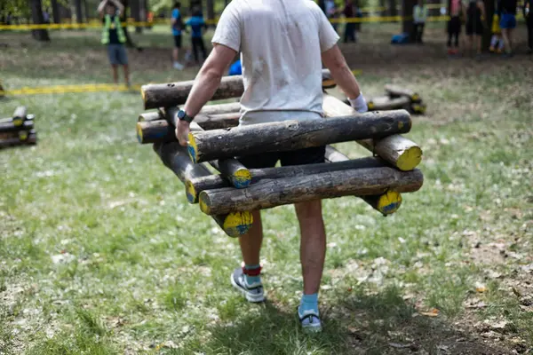 Genç sporcu engelli yarış pistinde kütük taşıyor..