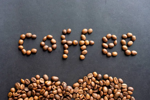 Siyah üzerine izole edilmiş kavrulmuş organik fasulyeden yapılmış İngilizce kelime kahvesi. Kahvehane için yazı tipi.