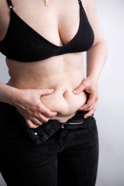 Şişman kadın karnı için üzülüyor. Kilolu bir kadın şişman karnına dokunuyor ve kilo vermek istiyor. Kilo diyeti için endişelenen şişman kadın.