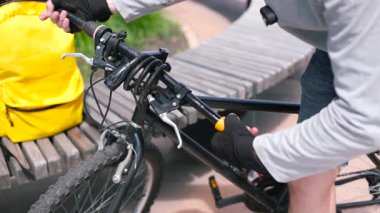 Bisiklet tamircisinin elleri yıpranmış gidonları değiştiriyor. Bisiklet tamiri, teşhis ve bisiklet bileşenlerinin ayarlanması. Çevre taşımacılığının elle bakımı