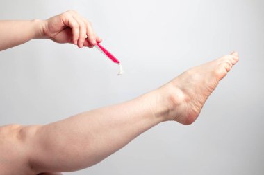 Pembe jiletle saçların sabunlu köpükle kaplı bacaktan çıkarılması işlemi