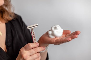 Pembe jiletle saçların sabunlu köpükle kaplı bacaktan çıkarılması işlemi