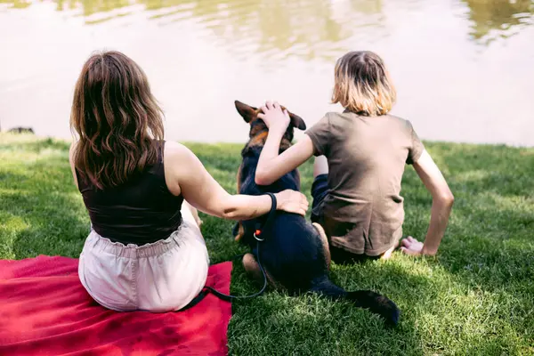 Anne ve çocuğu göl kenarındaki çimlerde dinleniyor.