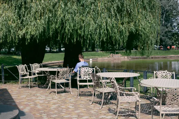 Genç adam gölün kenarındaki bir kafede oturuyor ve kahve içiyor..